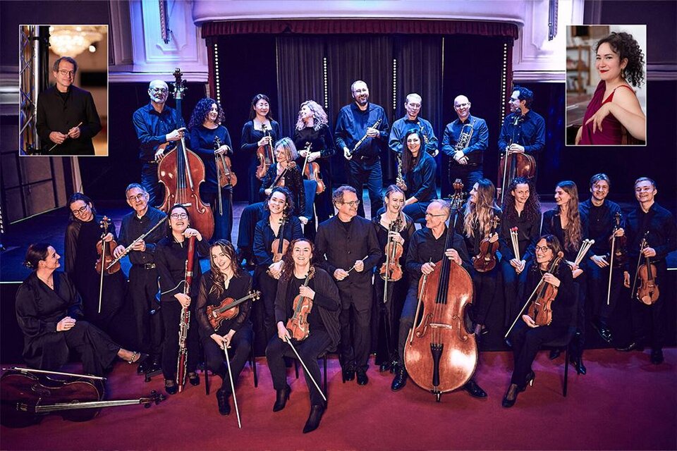 Eine Gruppe von Musikern steht auf der Bühne in formeller Kleidung. Im Hintergrund sind Instrumente zu sehen und die Atmosphäre wirkt festlich. | ©  Karina Benalcàsar und Miriam Kaczor