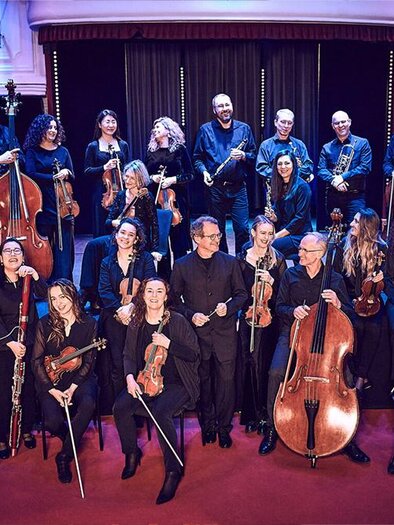 A group of musicians stands on stage in formal attire. In the background, instruments are visible and the atmosphere seems festive. | ©  Karina Benalcàsar und Miriam Kaczor