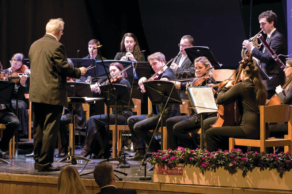 Ein Orchester spielt auf einer Bühne. Der Dirigent leitet die Musiker, die konzentriert notieren. | © Lions Club
