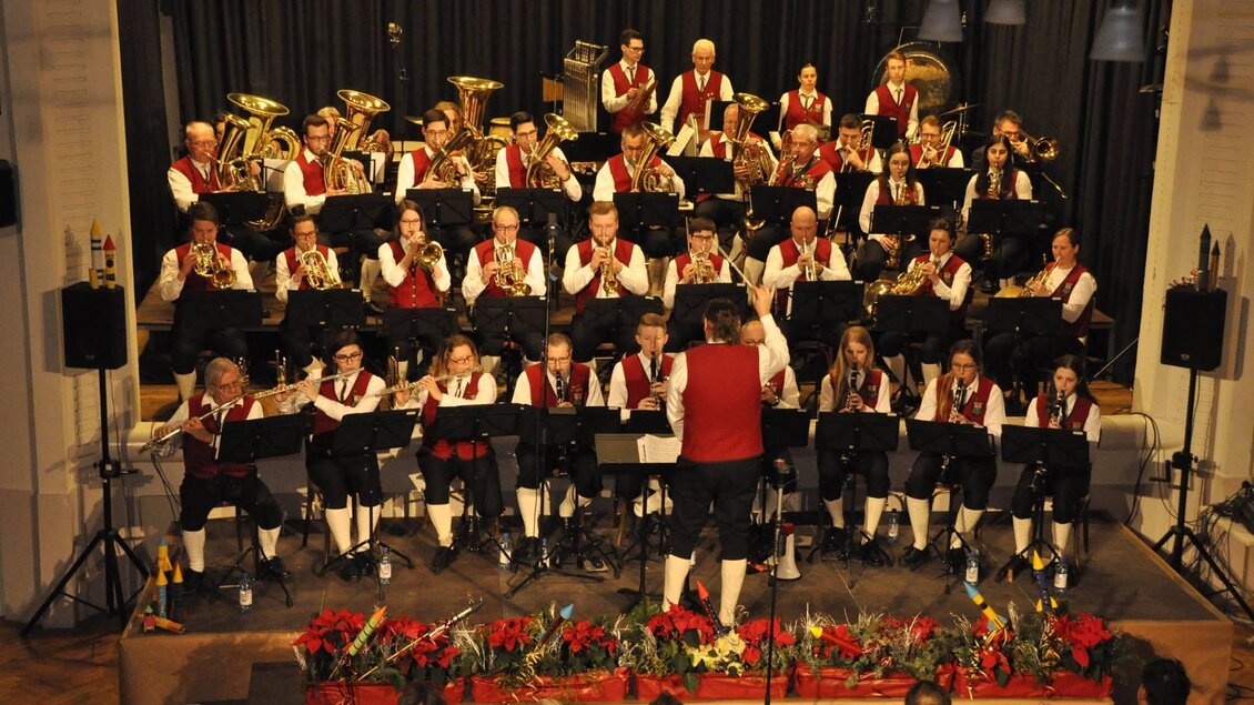 Ein Musikverein spielt auf einer Bühne. Die Musiker tragen traditionelle Kleidung und sind in froher Stimmung. | © GTK Mureck
