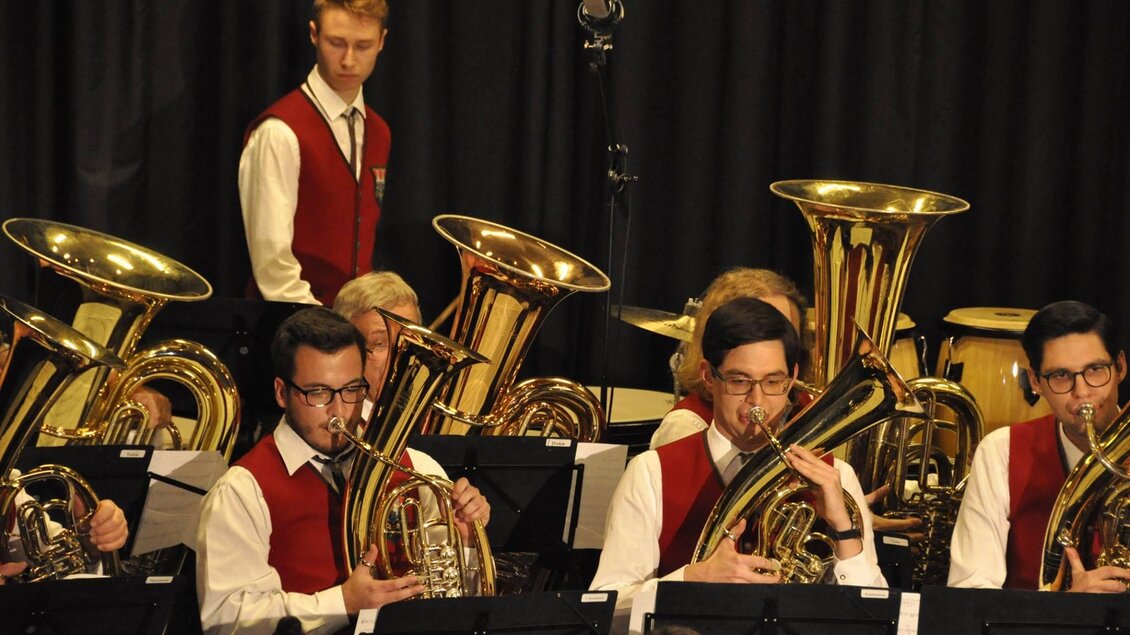 Eine Blaskapelle spielt auf der Bühne. Die Musiker tragen rote Westen und spielen verschiedene Blechblasinstrumente. | © GTK Mureck