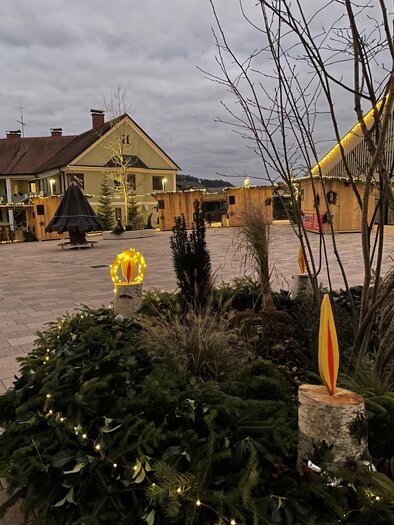 A festively decorated terrace with a beautiful house in the background. Green plants and lights create a cozy atmosphere. | © TV Südsteiermark