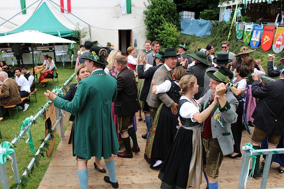 Eine festliche Tanzveranstaltung im Freien mit Menschen in traditioneller Kleidung. Die Stimmung ist lebhaft und fröhlich, umgeben von Festwagen und Dekoration. | © Stadtgemeinde Leoben
