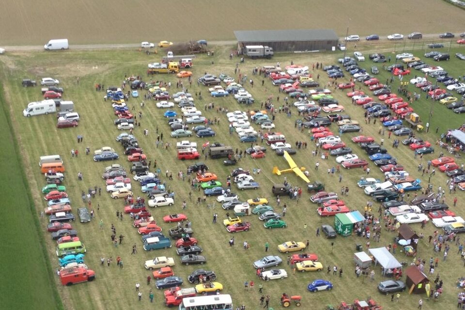 Eine große Automeile mit vielen verschiedenen Fahrzeugen auf einem Feld. Zahlreiche Besucher betrachten die Autos und genießen die Veranstaltung. | © SSW