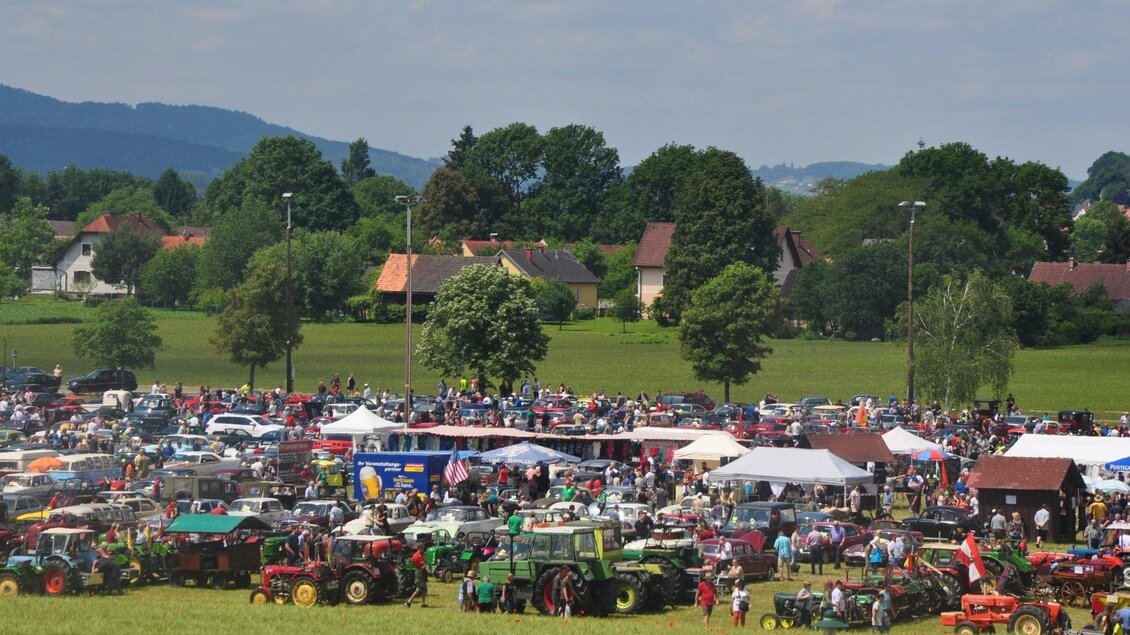 Eine große Versammlung von Menschen auf einem Feld, umgeben von zahlreichen Traktoren. Es gibt Zelte und eine grüne Landschaft im Hintergrund. | © SSW