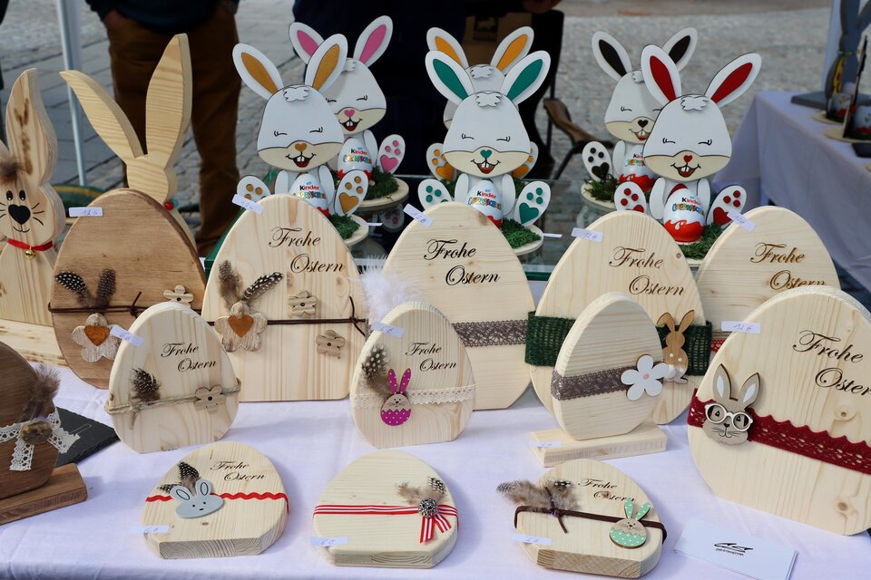 Eine bunte Auswahl an dekorativen Holzosterhasen und Eiern. Auf den Objekten sind fröhliche Muster und Ostergrüße zu sehen. | © Oststeiermark Tourismus