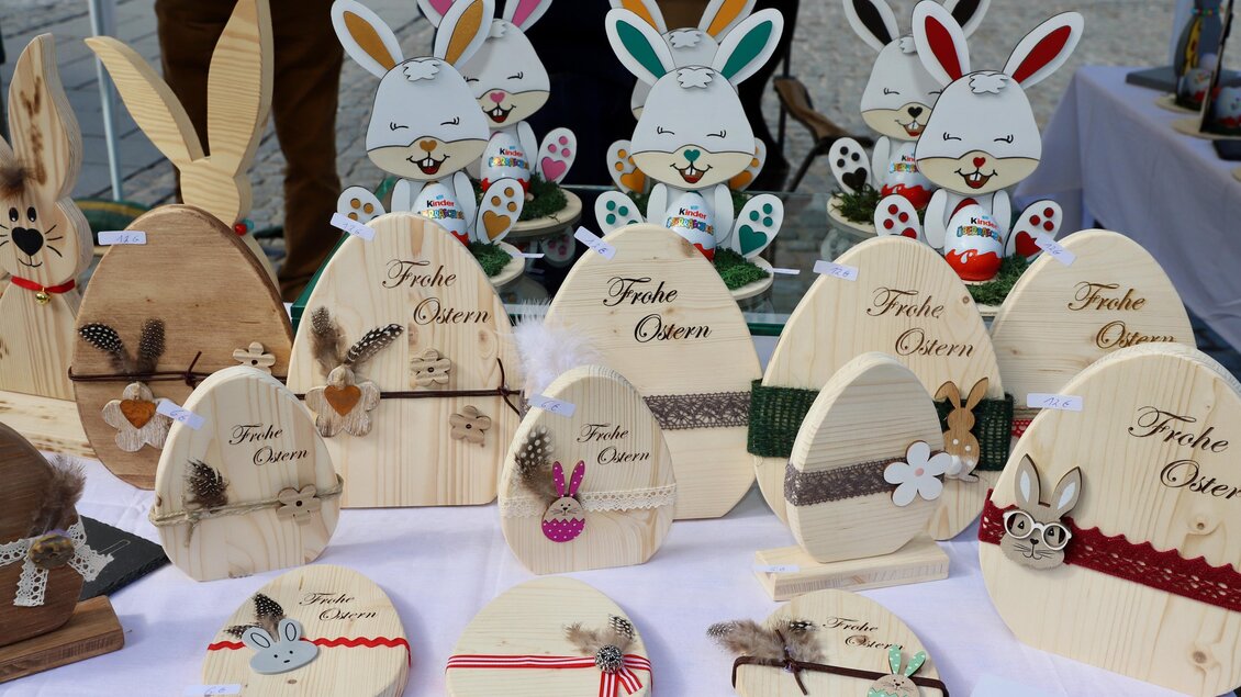 Eine bunte Auswahl an dekorativen Holzosterhasen und Eiern. Auf den Objekten sind fröhliche Muster und Ostergrüße zu sehen. | © Oststeiermark Tourismus
