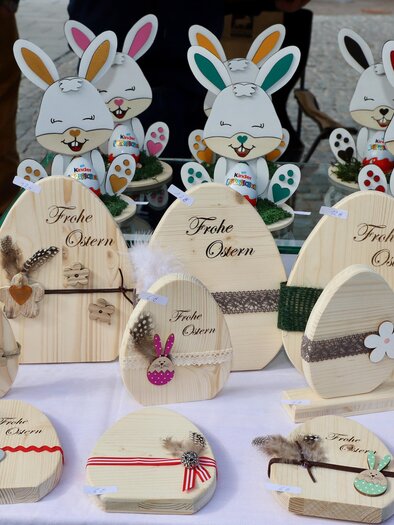 Eine bunte Auswahl an dekorativen Holzosterhasen und Eiern. Auf den Objekten sind fröhliche Muster und Ostergrüße zu sehen. | © Oststeiermark Tourismus