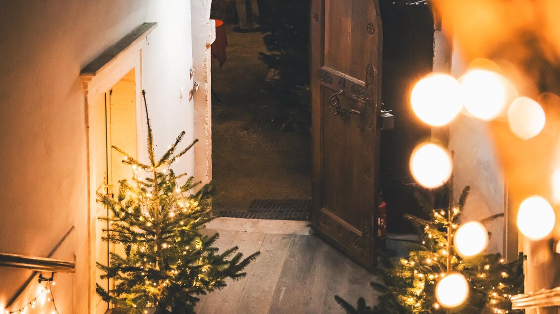 Eine gemütliche Eingangstür mit Weihnachtsbaum und Lichtern. Die Atmosphäre ist festlich und einladend. | © Ebner Maria