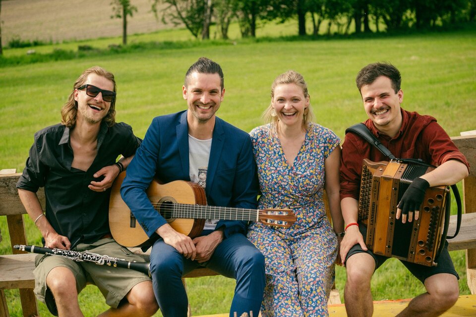 Ein junger Mann steht auf einer grünen Wiese umgeben von Bäumen. Im Hintergrund sind sanfte Hügel und ein bewölkter Himmel zu sehen. | © Manuel Hauer