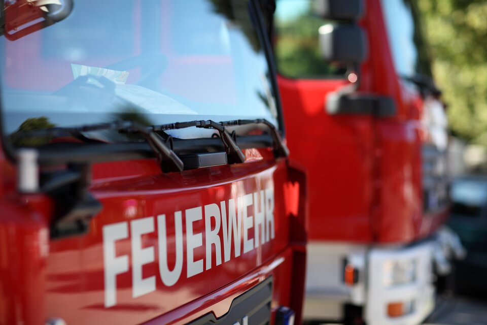 Ein rotes Feuerwehrfahrzeug mit der Aufschrift „FEUERWEHR“ im Vordergrund. Im Hintergrund sind weitere Feuerwehrautos sichtbar. | © Adobe Stock