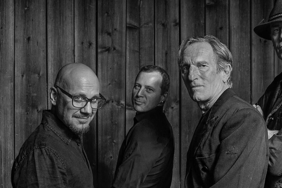 Fünf Männer stehen nebeneinander vor einer Holzwand. Sie tragen dunkle Kleidung und blicken in verschiedene Richtungen. | © Rauhnacht