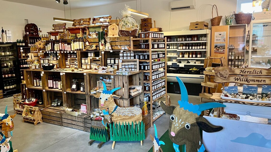 Ein gemütlicher Laden mit Holzregalen, die verschiedene Produkte wie Marmeladen und Gewürze anbieten. Dekorative Ziegenfiguren begrüßen die Besucher. | © Markus Lugitsch