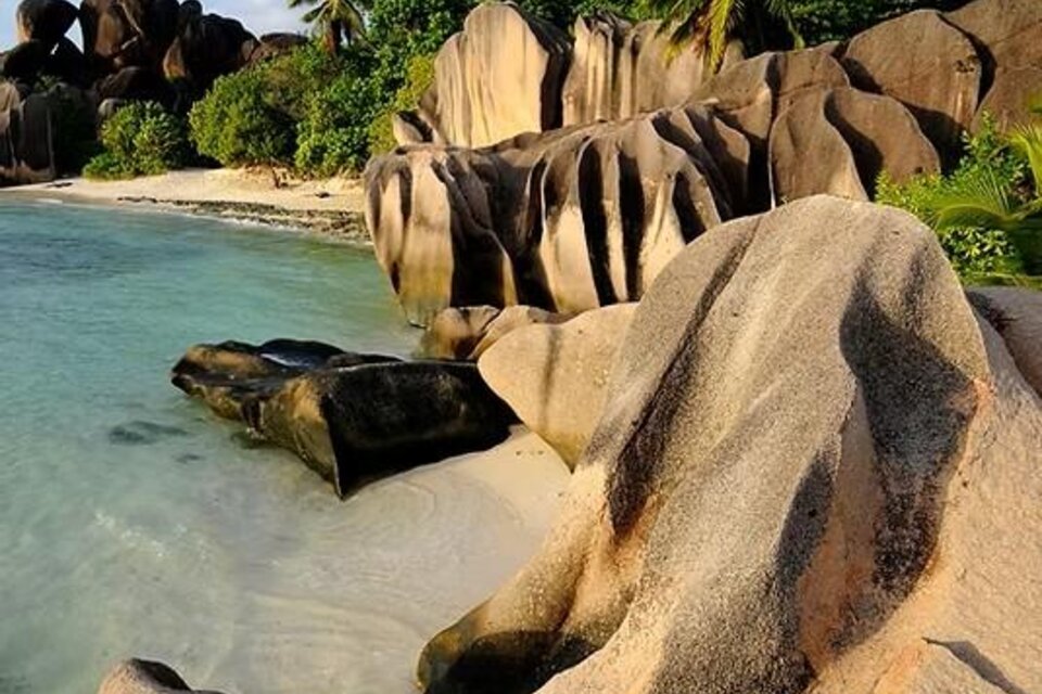 Eine malerische Küstenlandschaft mit markanten Felsen und klarem Wasser. Im Hintergrund sind grüne Palmen und eine ruhige Bucht zu sehen. | © Gerhard-Huber