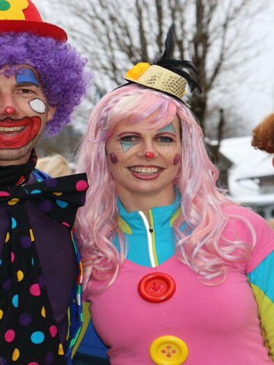 Drei fröhliche Personen in bunten Kostümen stehen zusammen. Sie tragen Clownschminke und lächeln in die Kamera. | © TVB Ausseerland Salzkammergut/Siegfried Zink