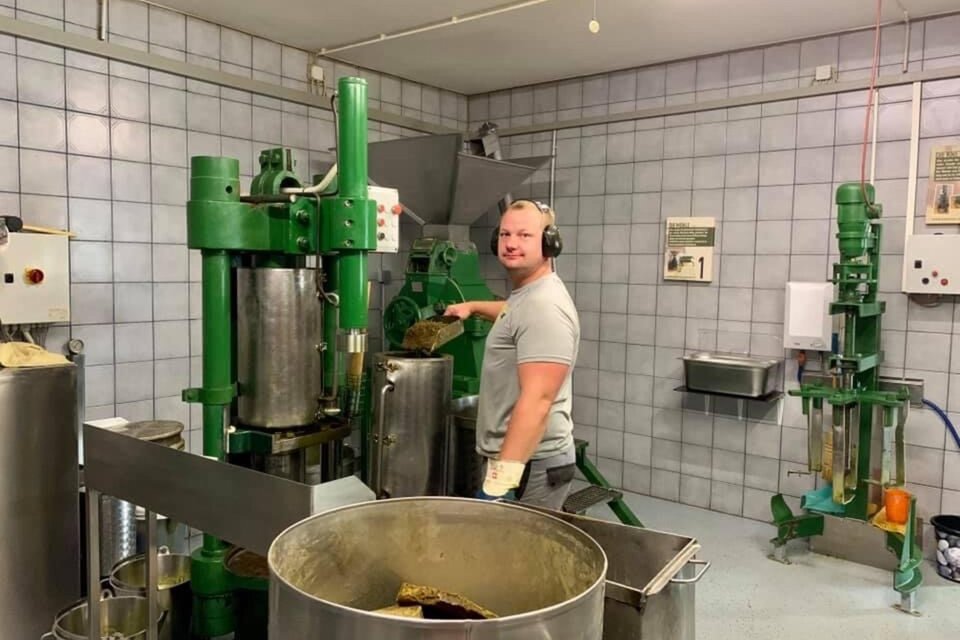 Ein Mann steht an einer großen grünen Maschine in einer Produktionshalle. Im Hintergrund sind weitere Maschinen und eine saubere, lichtdurchflutete Umgebung zu sehen. | © Bernd Resch