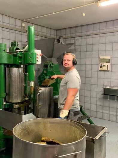A man is standing by a large green machine in a production hall. In the background, more machines and a clean, well-lit environment can be seen. | © Bernd Resch