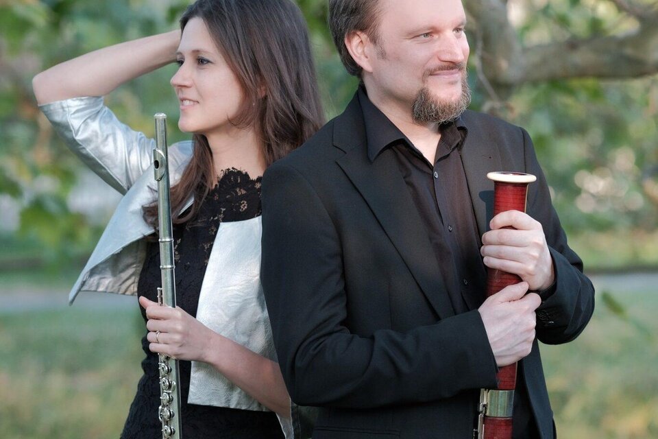 Ein lächelndes Paar sitzt im Publikum und applaudiert. Hintergrund mit weiteren Zuschauern, die ebenfalls erfreut wirken. | © achromaticphotography