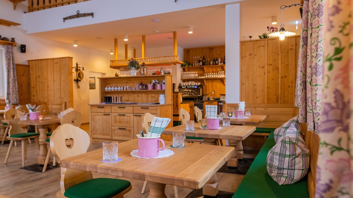 Ein gemütliches Restaurant mit Holzmöbeln und hellen Farben. Tische sind mit Gläsern und dekorativen Elementen gedeckt. | © www.zloam.at