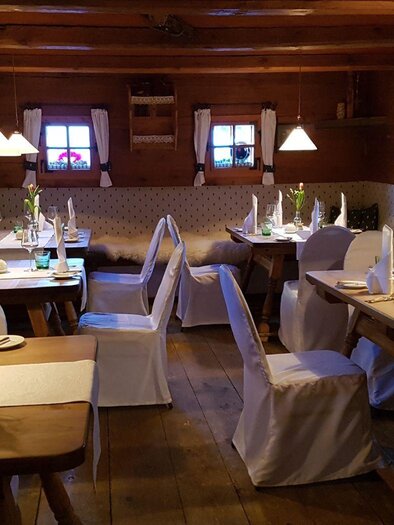 Ein gemütliches Restaurant mit Holzdekoration und sanfter Beleuchtung. Die Tische sind geschmackvoll mit Blumen und Geschirr gedeckt. | © Dominik Utassy