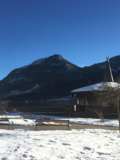 An idyllic winter landscape with a snow-covered ground and mountains in the background. In the foreground, there is a wooden gazebo next to a wooden bench. | © Tourismusverband Ausseerland