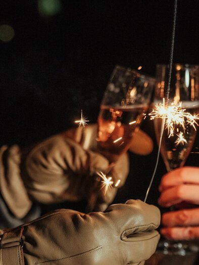 Two people toast with champagne glasses as sparks fly. The scene is festive and celebratory. | © Region Graz-studio draussen