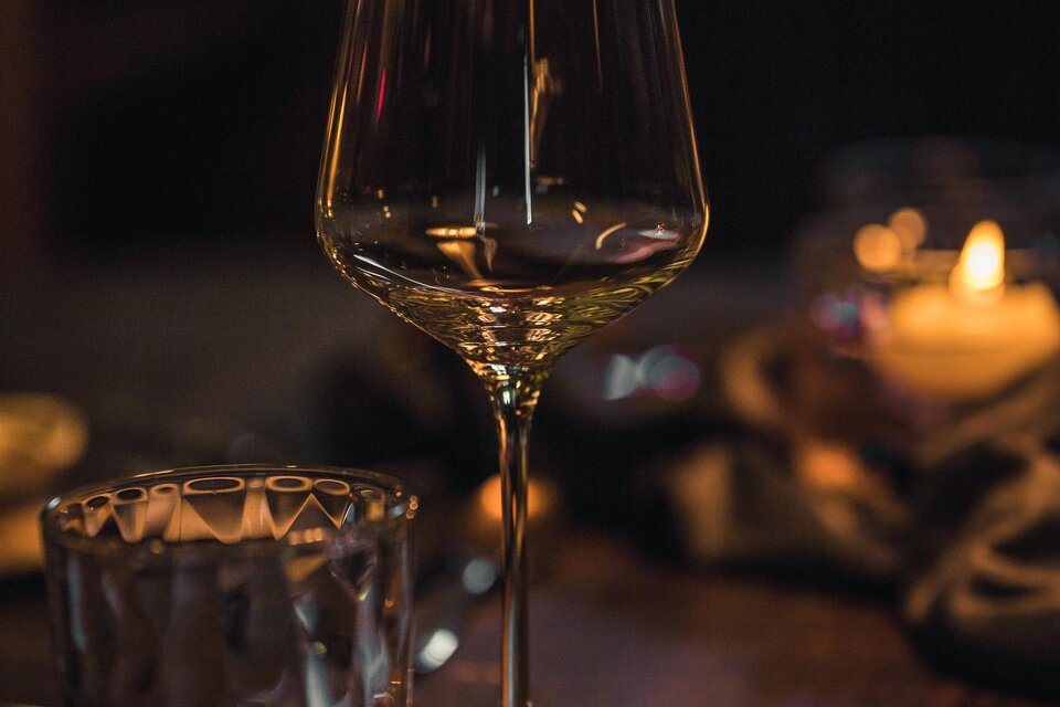 Ein elegantes Wein- und Wasserglas stehen auf einem schön gedeckten Tisch. Der Raum ist sanft beleuchtet, was eine gemütliche Atmosphäre schafft. | © Das Ursprung