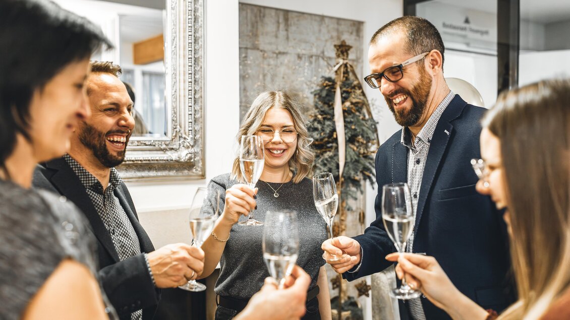 Eine Gruppe von fünf Personen feiert gemeinsam mit Sektgläsern. Sie lächeln und stoßen auf einen besonderen Moment an. | © Vulkanlandhotel Legenstein