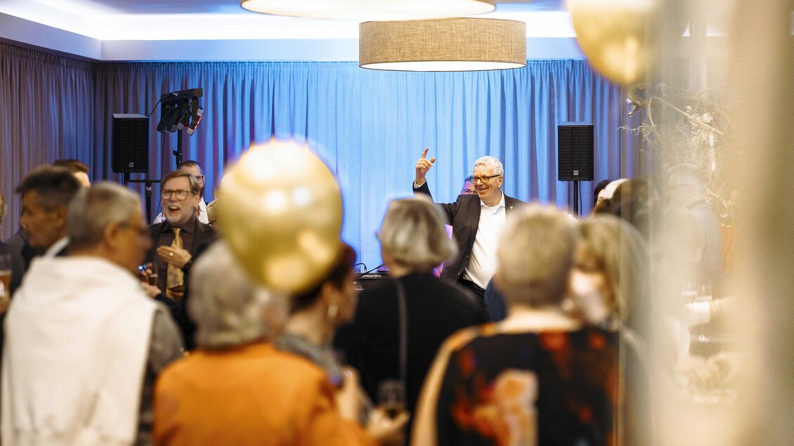 Eine fröhliche Feier mit vielen Gästen steht im Mittelpunkt. Der Mann vorne winkt und sorgt für gute Stimmung. | © Vulkanlandhotel Legenstein