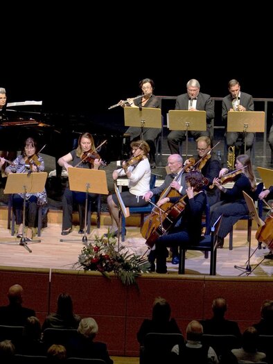 Ein Orchester spielt, während die Musiker ihre Violinen halten. Die Atmosphäre ist konzentriert und musikalisch. | © Walter Schindler