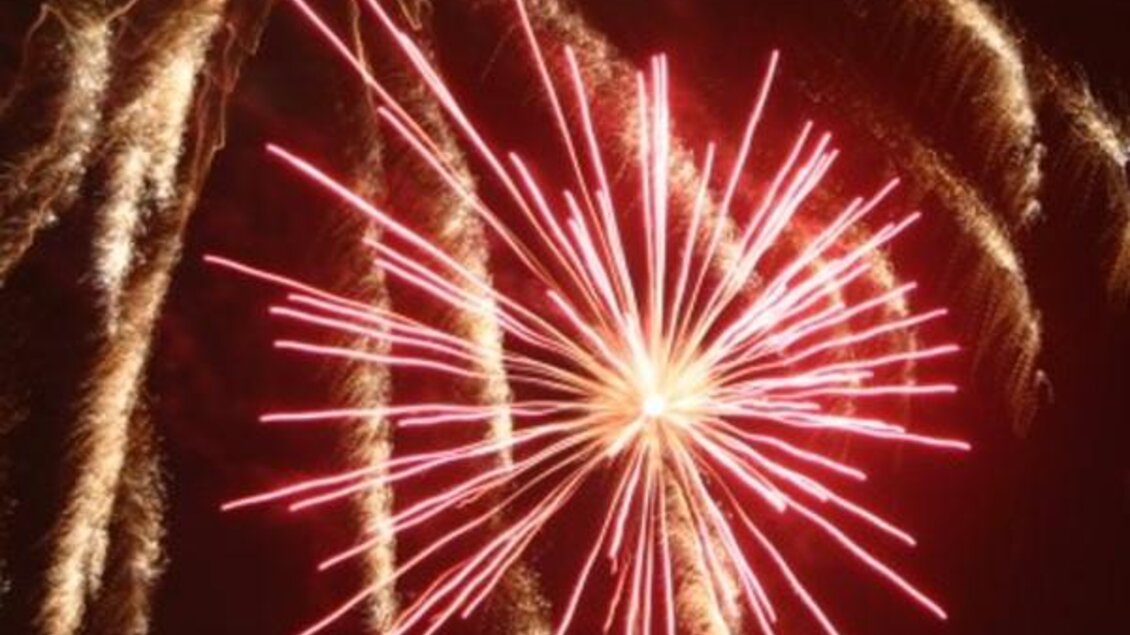 Ein Feuerwerk mit leuchtenden roten und goldenen Strahlen erhellt den Nachthimmel. Die Knaller bilden ein eindrucksvolles, symmetrisches Muster. | © Lederer