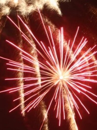 Ein Feuerwerk mit leuchtenden roten und goldenen Strahlen erhellt den Nachthimmel. Die Knaller bilden ein eindrucksvolles, symmetrisches Muster. | © Lederer