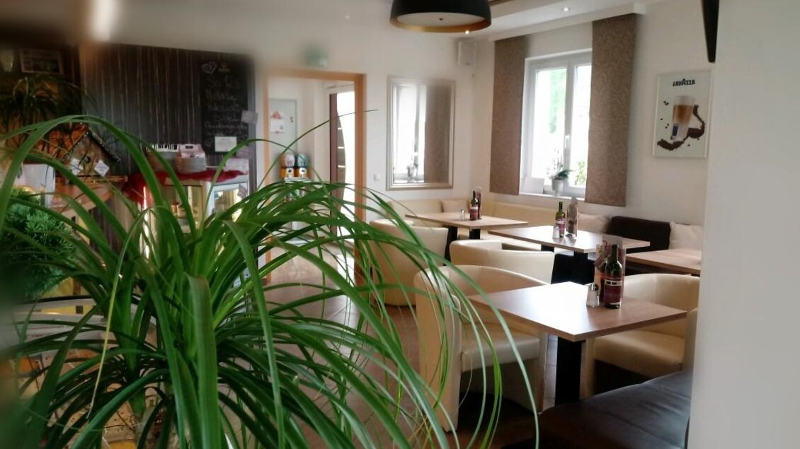 Ein gemütliches Restaurant mit hellen Tischen und Stühlen. Im Hintergrund sind Pflanzen und eine zentrale Beleuchtung zu sehen. | © Café Idylle