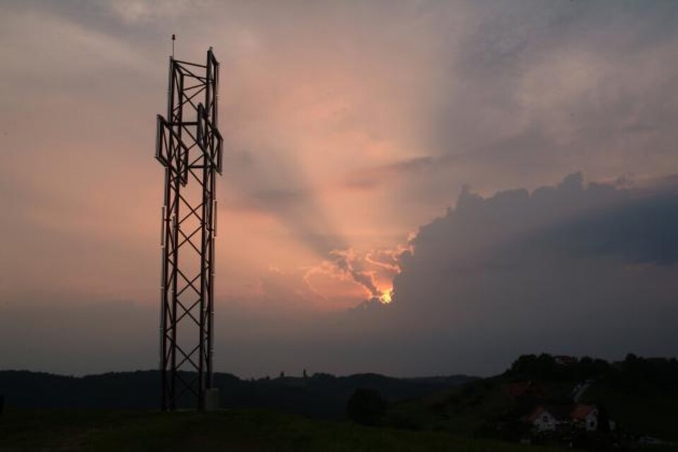 Ein Mobilfunkmast steht vor einem dramatischen Sonnenuntergang. Die Farben des Himmels wechseln von Grau zu warmen Orangetönen. | © Theater Hatzendorf