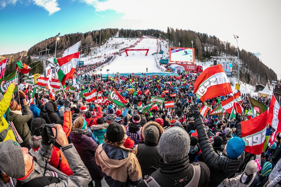 Eine große Menschenmenge jubelt auf einer Skisportveranstaltung. Viele Zuschauer halten Fahnen und feiern in einer festlichen Atmosphäre. | © Weltcup OK Semmering