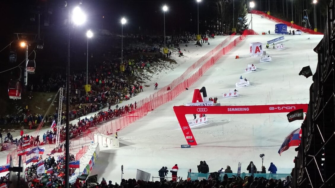 Eine beleuchtete Skiabfahrt mit vielen Zuschauern. Im Vordergrund ist die Rennstrecke mit rot gesicherten Bereichen zu sehen. | © Weltcup OK Semmering