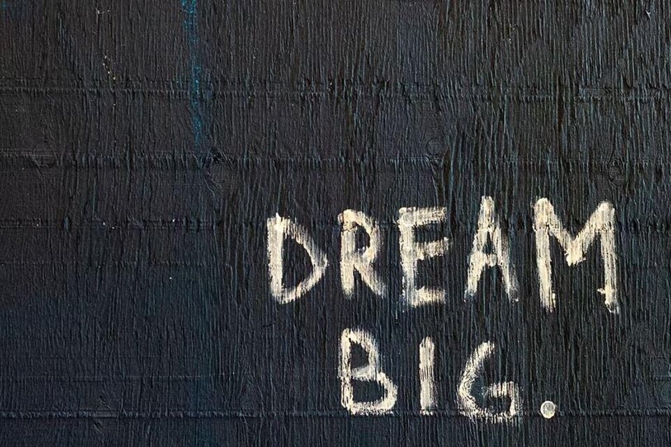 Ein schwarzer Hintergrund mit der weißen Aufschrift "DREAM BIG." in großen Buchstaben. Die Botschaft ermutigt dazu, große Träume zu haben. | © we.move