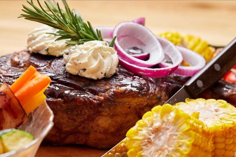 Ein saftiges Steak mit Kräuterbutter und roten Zwiebeln. Dazu frisches Gemüse und eine Kürbiskern-Kolbe. | © Hauser Kaibling