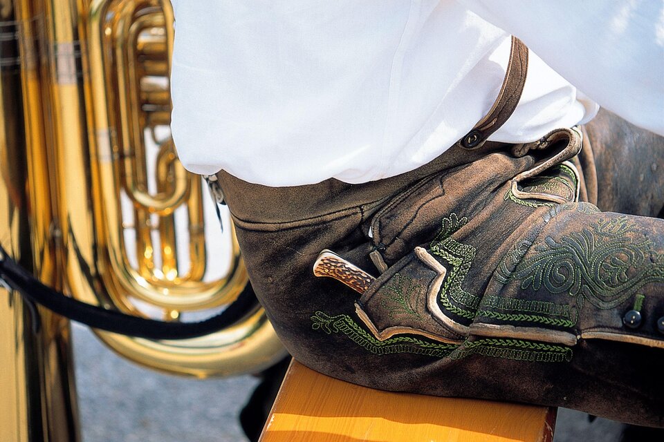Ein Teil eines traditionellen bayerischen Outfits mit schönen Lederhosen ist zu sehen. Im Hintergrund steht eine glänzende Tuba. | © Steiermark Tourismus