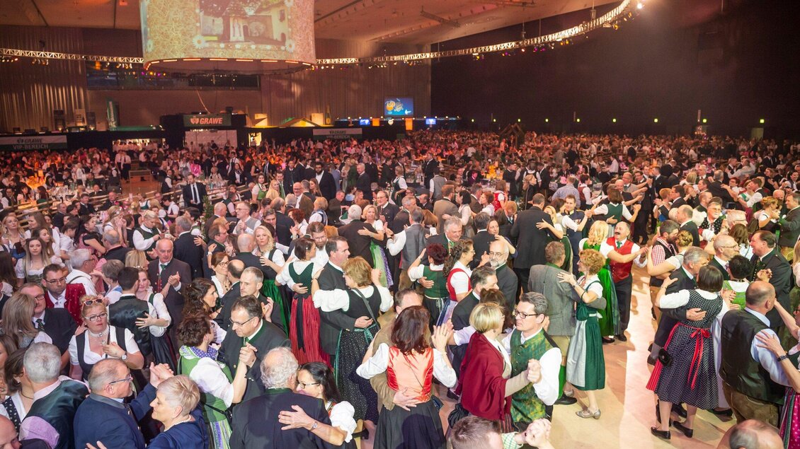 Eine große Menschenmenge tanzt in Tracht auf einer festlichen Veranstaltung. Die Stimmung ist fröhlich und lebhaft. | © Foto Fischer