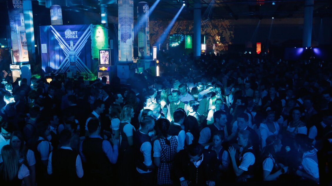 Eine lebhafte Party mit einer großen Menschenmenge. Die Atmosphäre ist festlich mit bunten Lichtern und Musik. | © Arthur