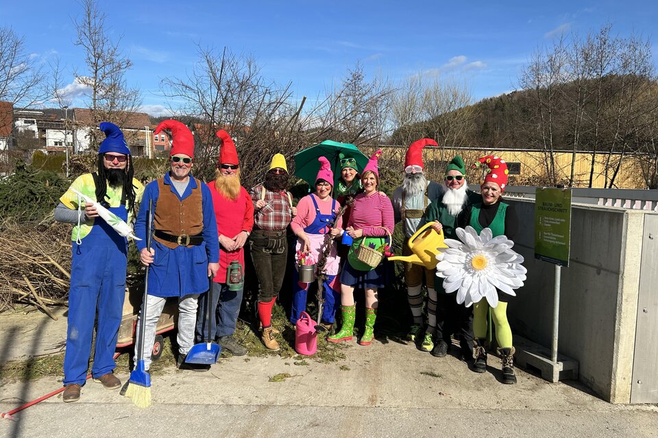 Eine Gruppe von Menschen in bunten Gartenzwerge-Kostümen steht fröhlich zusammen. Im Hintergrund sind Bäume und ein blauer Himmel zu sehen. | © Stern-Thaler Laientheater