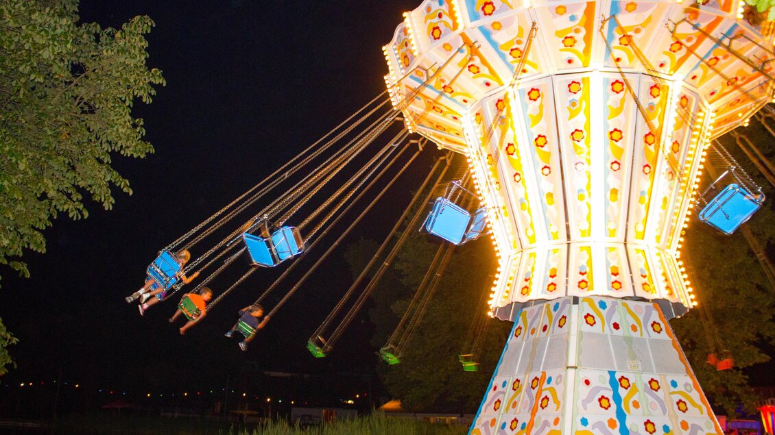 Eine bunte Karussellfahrt mit leuchtenden Lichtern, die Kinder hoch in die Luft schwingt. Der Hintergrund ist abends mit einem ruhigen See zu sehen. | © Sandra Brünner