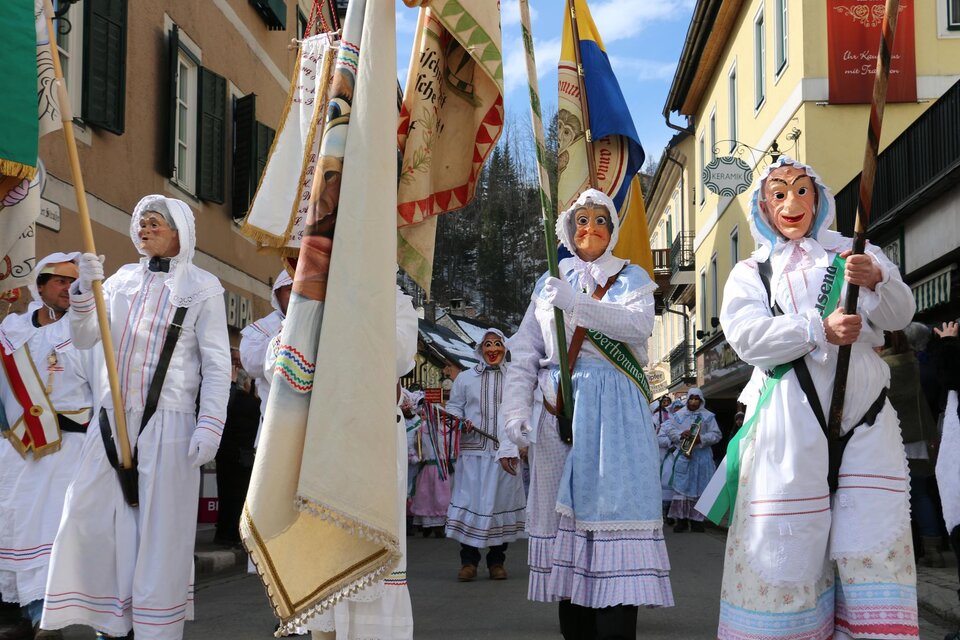 Eine Gruppe von Menschen in traditionellen Kostümen feiert einen Umzug. Sie tragen farbenfrohe Fahnen und Masken. | © TVB Ausseerland - Salzkammergut_Zink