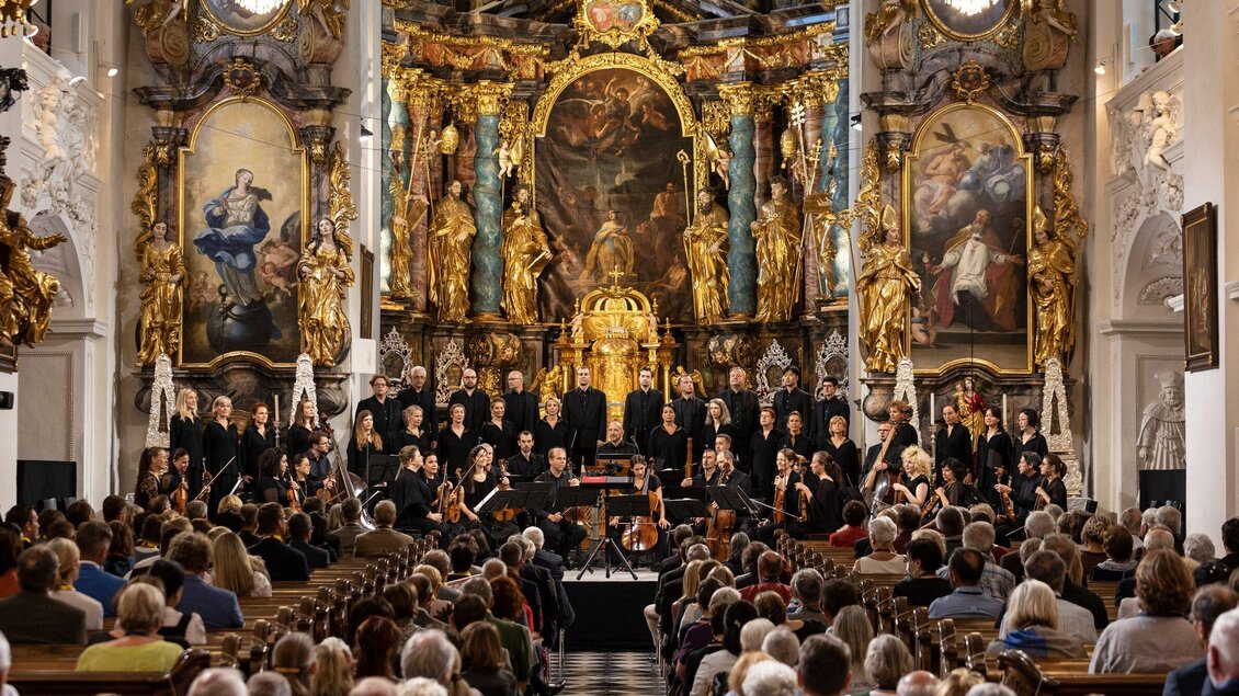 Ein Konzert in einer prächtigen Kirche mit vielen goldenen Verzierungen. Der Chor und das Orchester stehen auf der Bühne vor einem großen Publikum. | © Nikola Milatovic