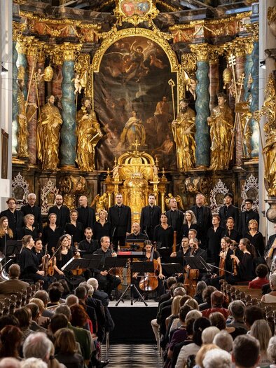 Ein Konzert in einer prächtigen Kirche mit vielen goldenen Verzierungen. Der Chor und das Orchester stehen auf der Bühne vor einem großen Publikum. | © Nikola Milatovic