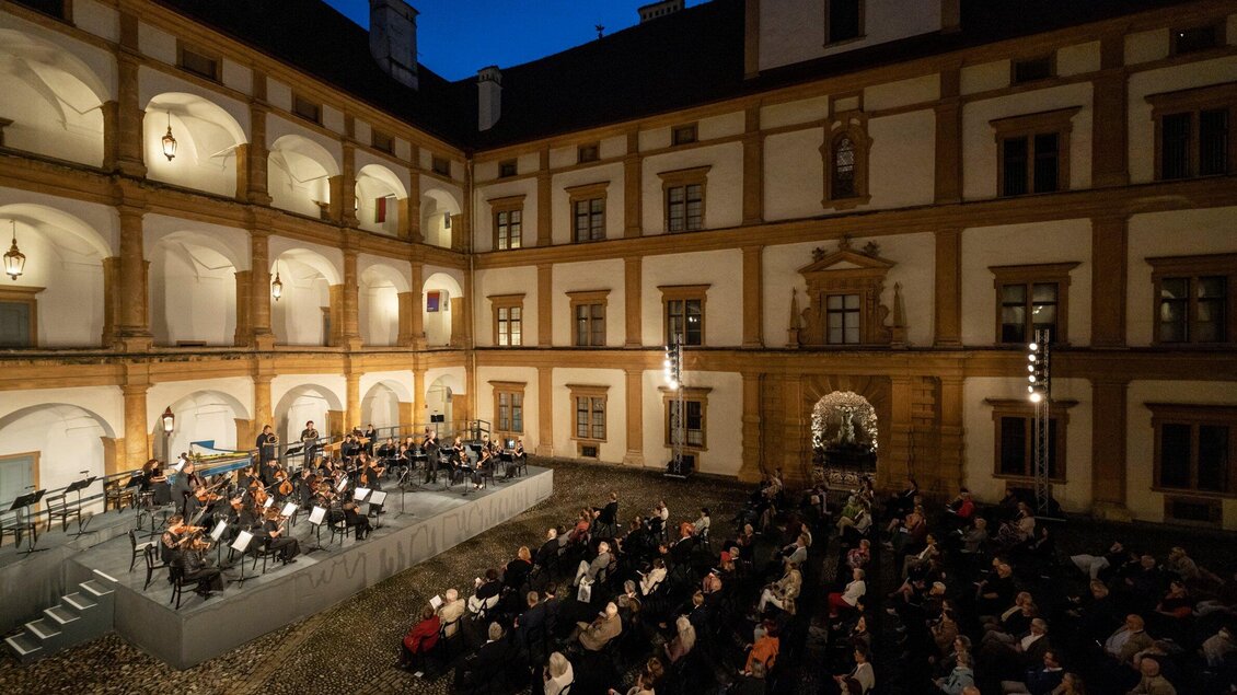 Ein Orchester spielt auf einer Bühne im Innenhof eines historischen Gebäudes. Die Zuschauer sitzen in Reihen und genießen das Konzert bei Nacht. | © Nikola Milatovic