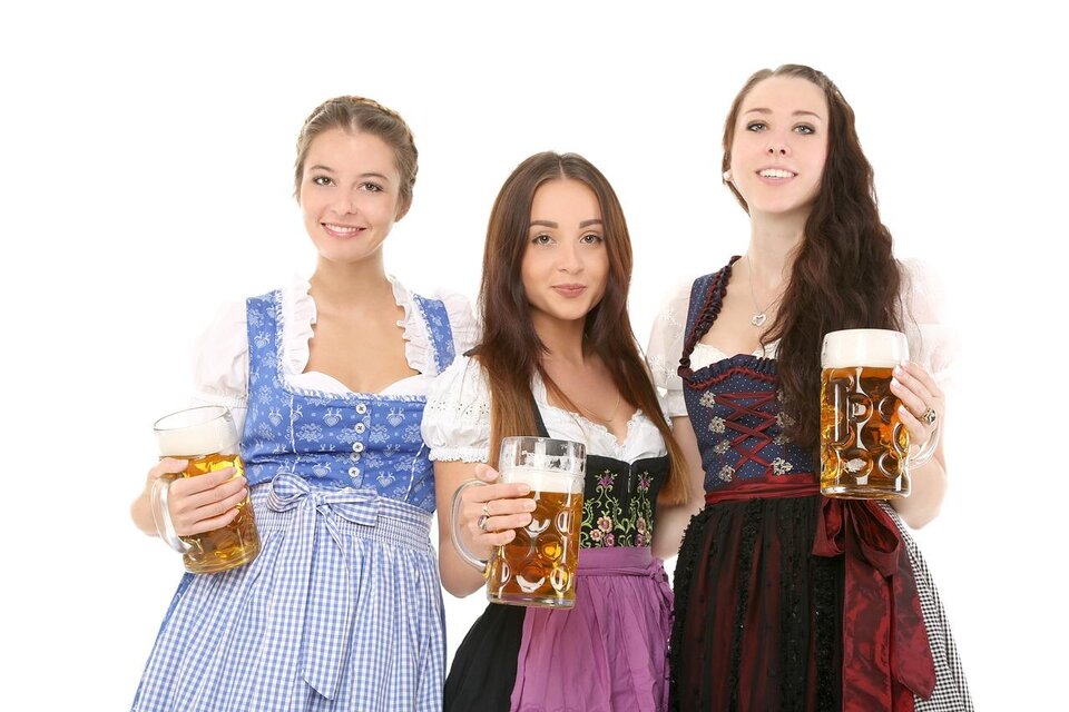 Drei Frauen in traditionellen bayerischen Trachten halten große Bierkrüge. Sie lächeln fröhlich und strahlen eine festliche Atmosphäre aus. | © Pixabay