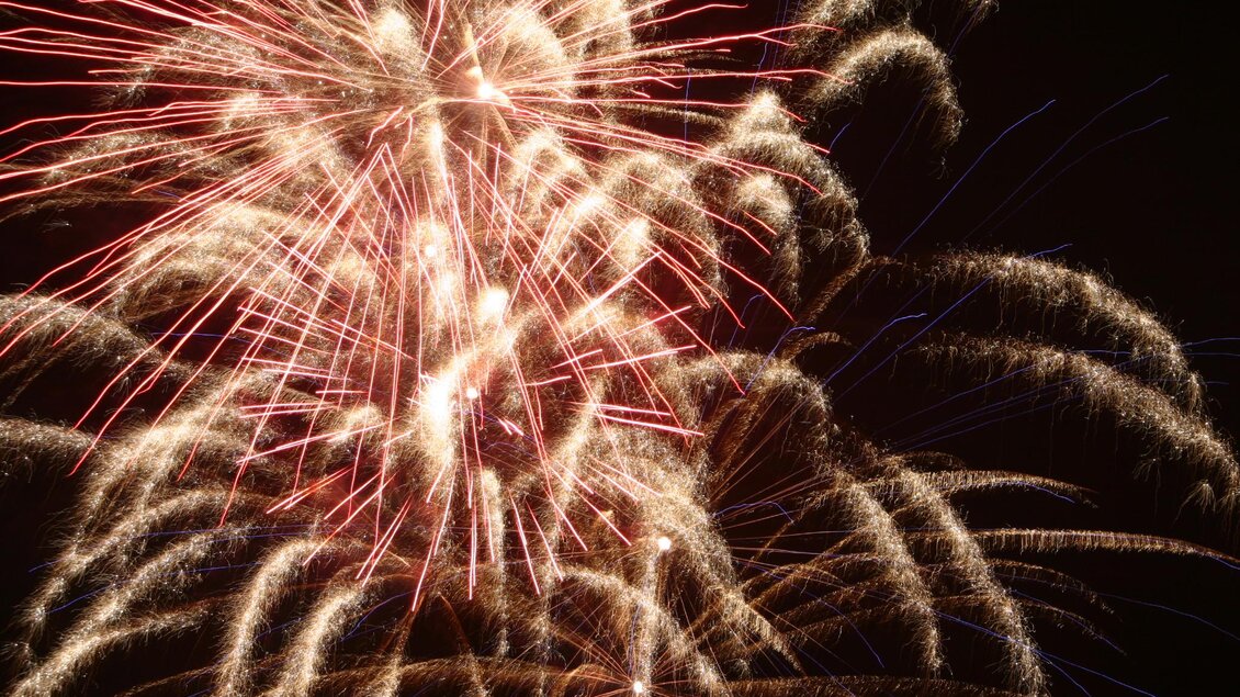 Ein spektakuläres Feuerwerk leuchtet am Nachthimmel. Die bunten Funken strahlen und erzeugen ein festliches Ambiente.