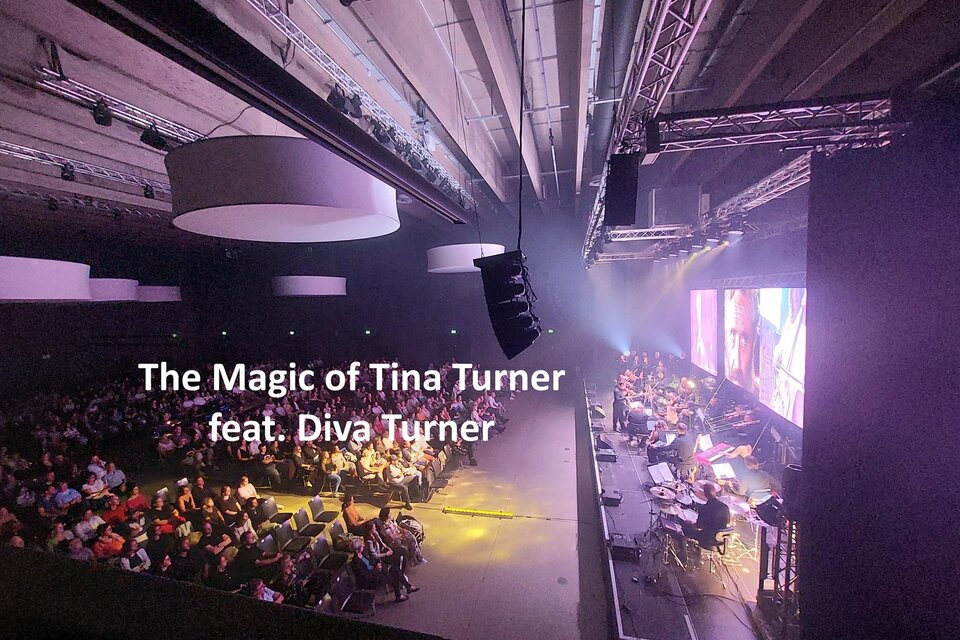 Ein Livemusik-Event mit einer großen Menschenmenge. Auf der Bühne sind Lichter und Instrumente zu sehen, während die Performance läuft. | © Tina Turner